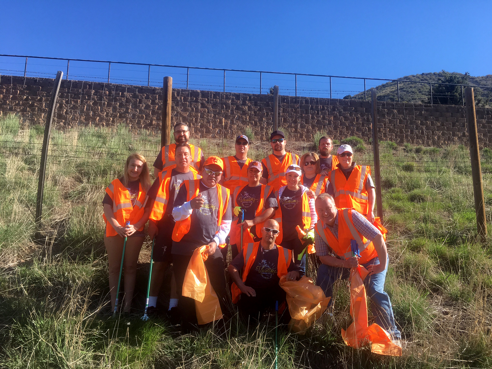 Group of associates in orange safety vests posing for a picture after a roadside clean-up event