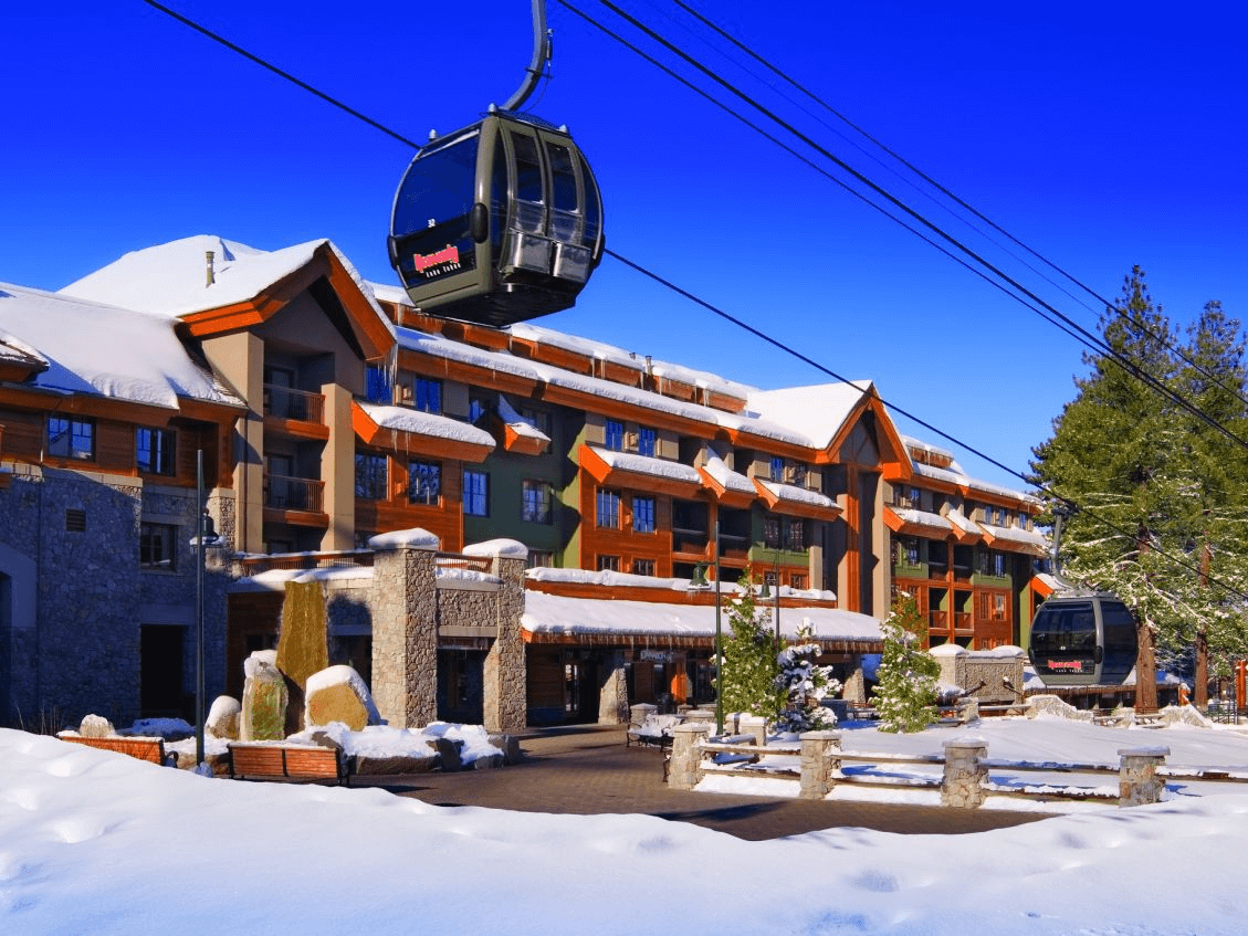 A stunning view of the Marriott Grand Residence Club in Lake Tahoe during a serene winter morning, with snow-covered mountains and glistening lake waters.